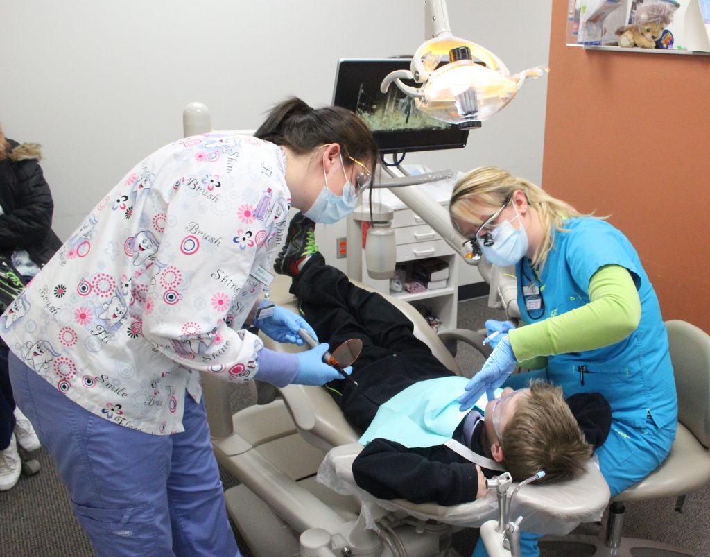 CVTC dental hygienist students Kelsey Wirth, right, and Megan Liss work on cleaning the teeth of Hunter Derleth, 8, of Osseo.