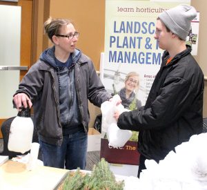 CVTC Horticulture Club students Olivia Myers, left, and Nate Schwartz prepare white spruce seedlings to be given away at the Earth Day event.