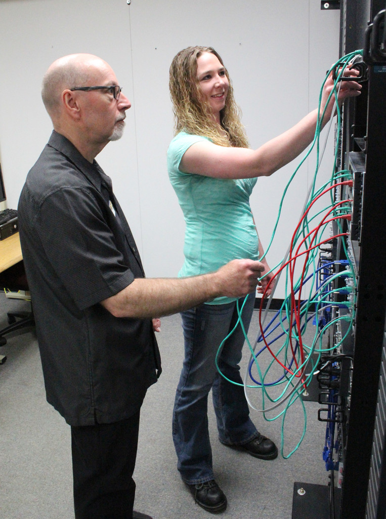 Cheri Bremness works with IT-network specialist Instructor Brian Goodman on connecting a series of servers in a lab at Chippewa Valley Technical College.