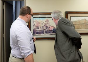Matt Hoy, left, shows Kristoffer Hellum, images of the Schlegelmilch Building, which stood on the southwest corner of Barstow and Eau Claire streets. Dr. Hans Christian Midelfart practiced there from 1900 to 1928.