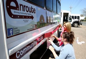 Hayes, right, and fellow UW-Stout student Melissa Cross apply graphics on a Dunn County Transit bus.