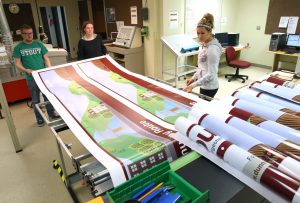 From left, Matthew Stoutenburg, Melissa Cross and Kelsy-Ann Hayes print graphics in a UW-Stout lab for Dunn County Transit buses.