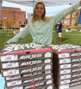 Taylor Pomasl, secretary of the UW=Eau Claire chapter of the Society of Professional Journalists, displays some of the pizza that fed students who were willing to relinquish (temporarily) their First Amendment rights.